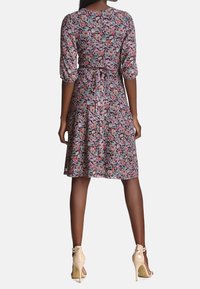 Květinové šaty s tříčtvrtečními nabíranými rukávy, zvýrazněným pasem, délky do kolen a černým pozadím. V kombinaci se světle béžovými lodičkami.