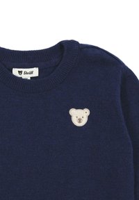 Felpa lavorata a maglia blu navy con scollo rotondo e un patch ricamato a forma di testa di orso color beige chiaro sulla parte superiore sinistra del petto.
