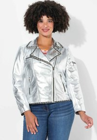 Silberne metallische Motorradjacke mit tailliertem Design, Reißverschlusstaschen und strukturierten Details entlang der Nähte und des Kragens.