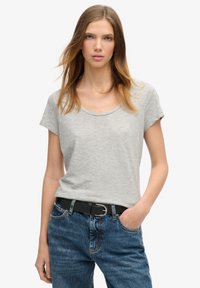 T-shirt gris clair à manches courtes avec encolure scoop, fabriqué dans un matériau doux. Associé à un jean en denim bleu taille haute et à une ceinture noire.