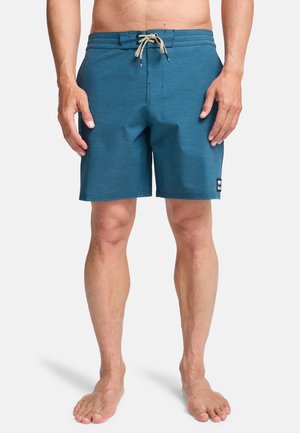 Blue swim shorts with an elastic waistband and drawstring, featuring a flat front, side pockets, and a small logo patch.