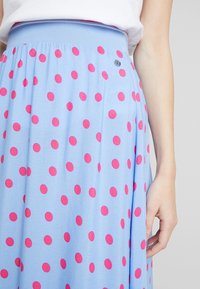 Gonna azzurro chiaro con grandi pois rosa, dotata di una vita elastica e un piccolo dettaglio a logo in metallo sul lato. Tessuto dalla texture morbida.