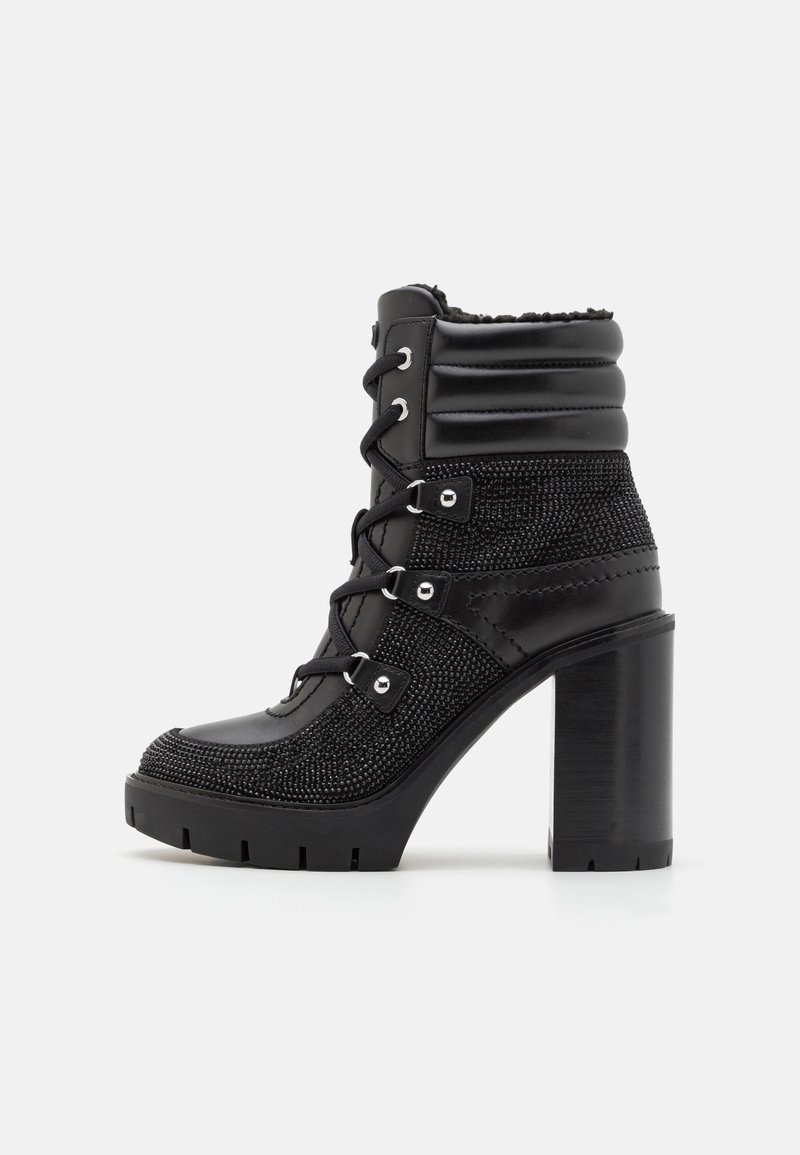 Botte courte à talons hauts noire avec un dessus en tissu texturé, devant lacé, col rembourré et semelle épaisse en caoutchouc. Comprend des œillets et des accents en métal.
