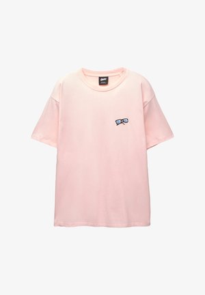 Tricou scurt cu mânecă roz, din bumbac. Prezintă un design brodat cu ochelari pe partea stângă a pieptului. Culoare rotundă la gât și croială lejeră.