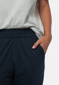 Grijze T-shirt met korte mouwen, gecombineerd met marineblauwe sweatpants met elastische taille, voorzien van zijzakken en een zachte, gladde textuur.