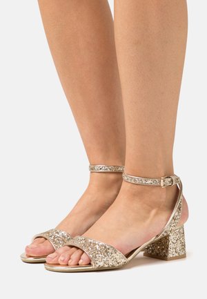 Gold glitter strappy sandals with an ankle buckle, open toe, and a chunky heeled design featuring a textured finish.