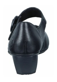 Zapato de cuero negro con punta redondeada, tacón bajo y correa ajustable. Textura suave con un detalle de logo circular en la parte trasera.
