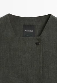 Tmavě šedá texturovaná košile se čtvercovým výstřihem, černým knoflíkem u límce a štítkem "Massimo Dutti Made in Portugal" uvnitř.