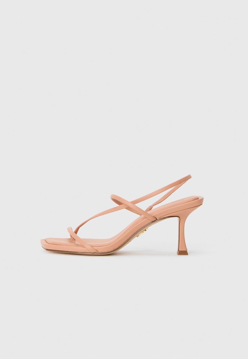 Nude rosa hæl sandal med tynde krydssnore og slingback, vist mod en hvid baggrund.