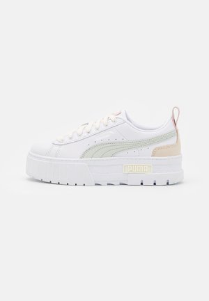 Baskets à plateforme blanches avec bande Puma vert clair, patch beige au talon, devant à lacets et semelle épaisse texturée.