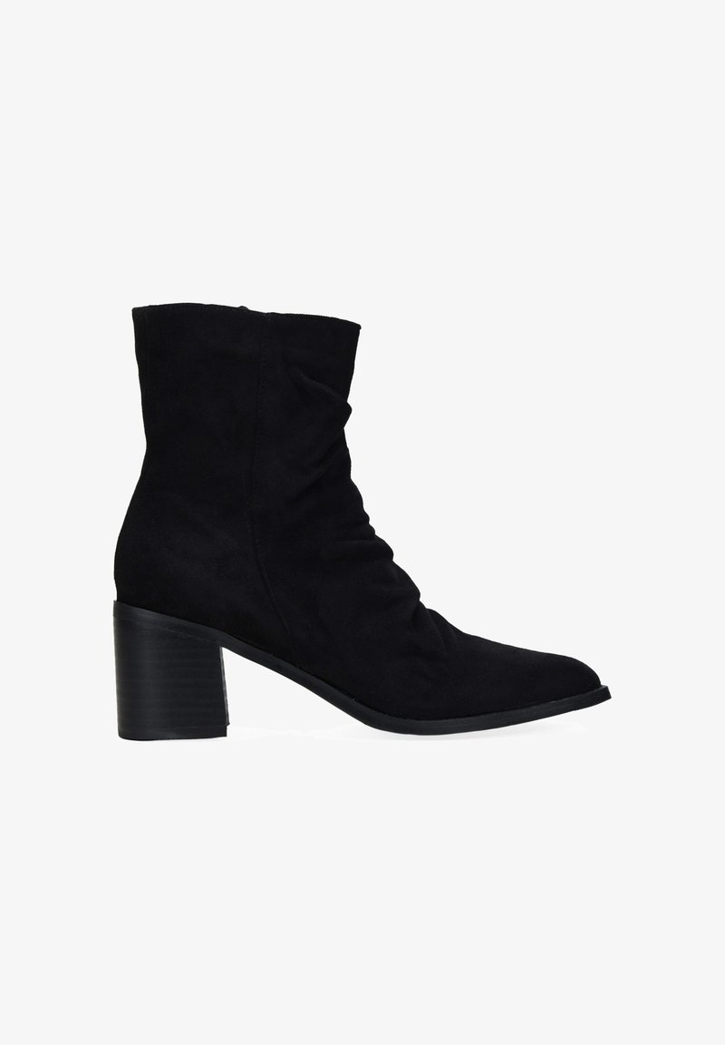 Botín negro de ante hasta el tobillo con un diseño arrugado, puntera afilada y un tacón grueso y estriado, con textura suave y sin herrajes visibles.