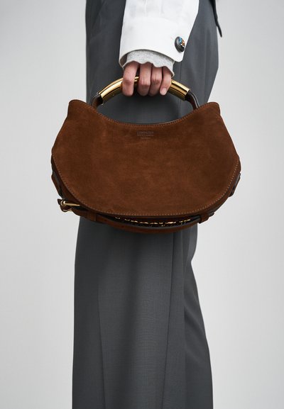 Brown suede handbag with a semi-circular shape. Features a gold-tone handle and adjustable strap. Embossed logo on the front.