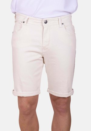 Pantalones cortos de denim blanco con dobladillos enrollados, usados por una persona con una camisa blanca metida, mostrando detalles de botones frontales y bolsillos.