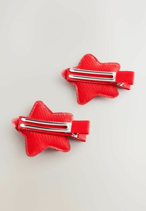 Red star-shaped hair clips made of textured fabric with metal clips, featuring a ribbed ribbon accent and a glossy finish. Two pieces shown.