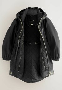 Giacca nera isolante con cappuccio, con interno trapuntato, hardware con accenti dorati e dettagli del logo lungo la cerniera e l'orlo.