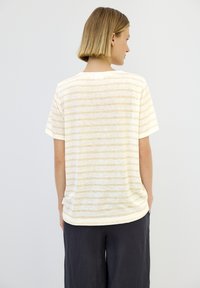 Stribet t-shirt i blødt, let stof; med vandrette linjer i lys gul og hvid; afslappet pasform med korte ærmer og rundet kant.
