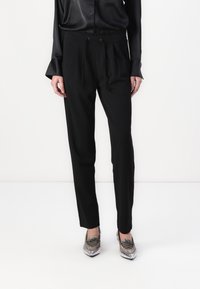 Svarta byxor med dragsko i midjan, slim fit och sidofickor. Pairade med en blank svart blus och metalliska skor.