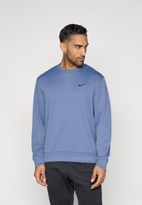 Sweatshirt à manches longues Nike en tissu bleu doux avec un col rond, des poignets côtelés et un petit logo noir sur la poitrine gauche.