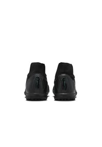 Black athletic shoes with a textured surface, high-top design, and green accents. Features a rubber sole with raised studs for traction.