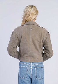 Grijs suede cropped jack met een grote kraag, voorzakken en subtiele branding op de achterkant. Gekocht met lichtblauwe denim jeans.