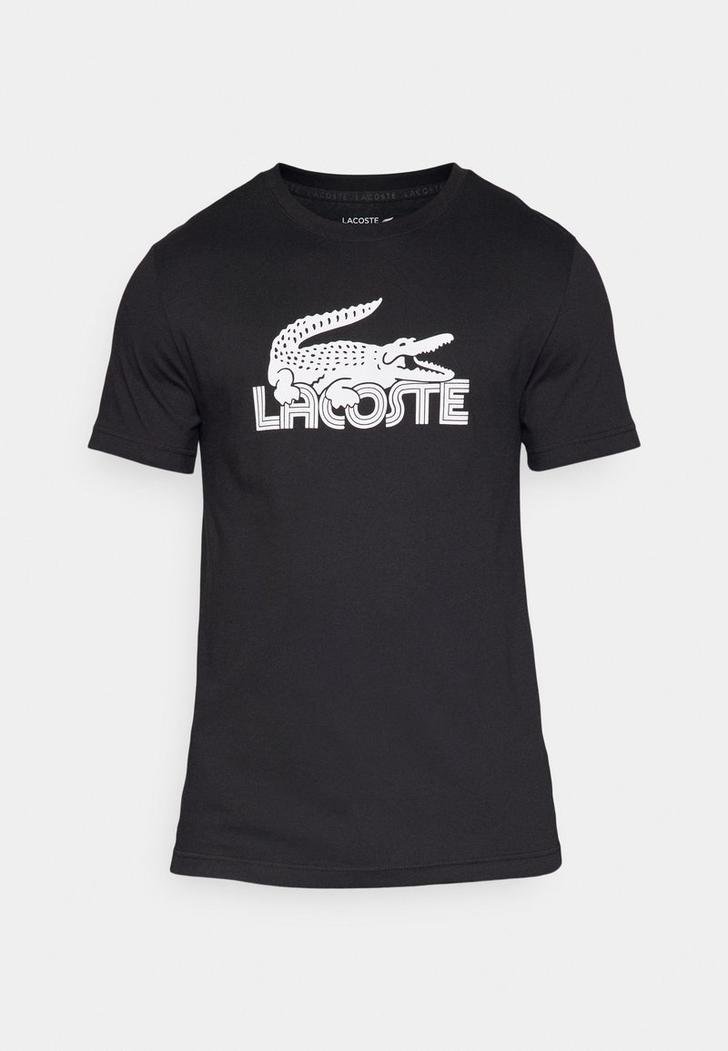 Camiseta de algodón negra con el logo del cocodrilo blanco de Lacoste en un estilo retro. Diseño de manga corta y cuello redondo.