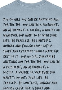 T-shirt en coton bleu clair avec un texte noir dans une police manuscrite en gras, comprenant des phrases motivantes sur la poursuite des objectifs et des ambitions.