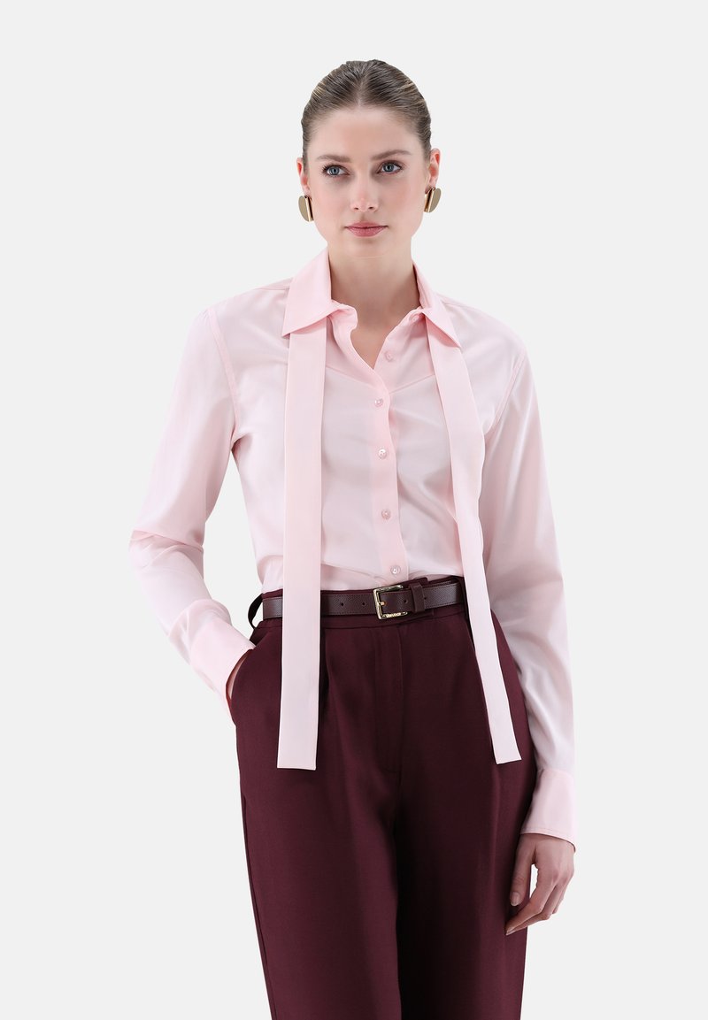Light pink button-up shirt with long collar ties, paired with burgundy high-waisted trousers and a brown belt. Smooth fabric texture.