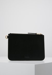 Pochette en cuir noir avec une texture lisse, zip de fermeture et quincaillerie dorée. Présente un logo embossé en bas.