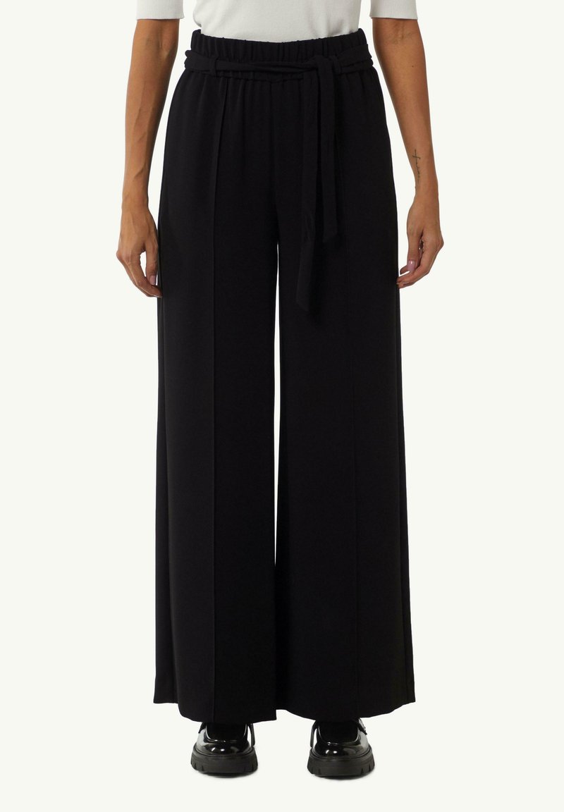 Schwarze, weit geschnittene Hosen mit einem hohen, elastischen Bund und Bindegürtel. Hergestellt aus weichem Stoff, der eine glatte Textur und klare Linien aufweist.