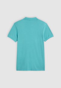 Polo turquoise uni à manches courtes vu de dos sur un fond gris clair.