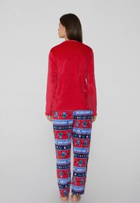 Czerwony miękki długi rękaw w połączeniu z niebieskimi wzorzystymi piżamowymi spodniami z świątecznymi grafikami, lizakami i kolorowymi światełkami.