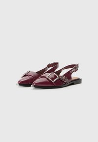 Burgundy slingback shoes with pointed toes, featuring silver buckles and flat black soles, made from smooth synthetic material.