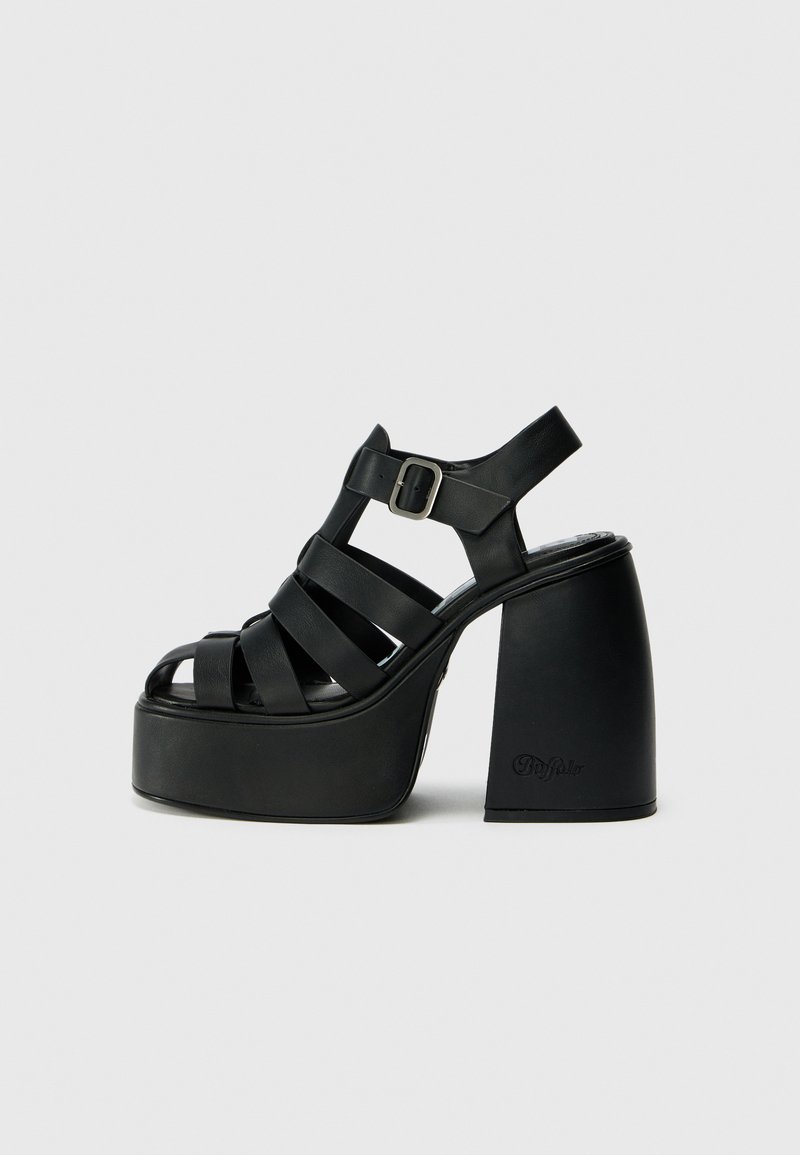 Black platform sandals with wide crossed straps, adjustable ankle strap, and chunky heel. Made of smooth material with minimal detailing.
