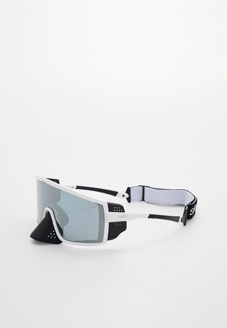 Gafas de deporte blancas con lentes oscuros, acentos negros y una distintiva protección para la nariz. Correa ajustable con una superficie texturizada para un mejor agarre.