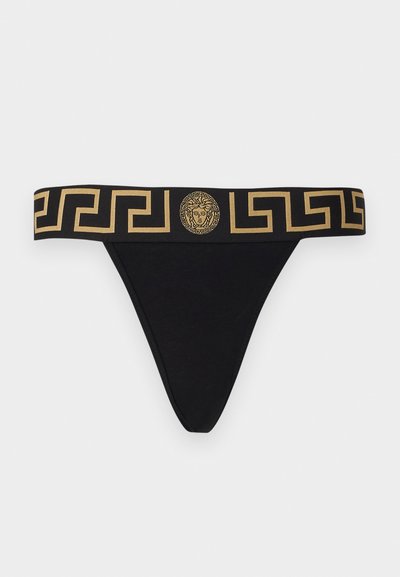 Black thong underwear with a wide gold patterned waistband featuring a lion head emblem and Greek key design. Cotton blend material.