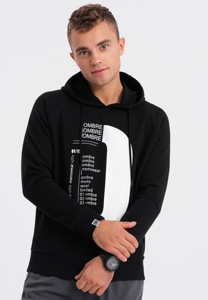 Sudadera negra con un diseño gráfico en la parte frontal que presenta texto blanco y una gran forma blanca. Tejido suave, capucha con cordón y puños acanalados.