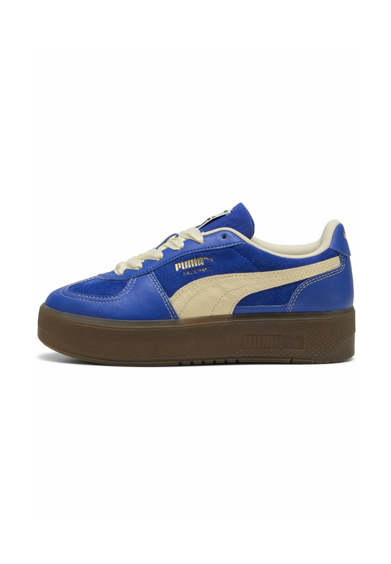 Sneakers din piele albastră cu accente bej, prezentând o talpă texturată maro, șireturi albe și un detaliu cu logo auriu pe lateral.