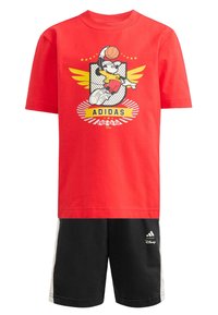 Červené tričko s krátkym rukávom s kresleným obrázkom basketbalistu a žltými detailmi, doplnené čiernymi šortkami s bielymi bočnými pásmi a logom.