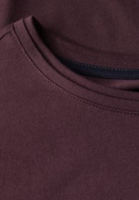 Burgundy bomulds T-shirt med rund halsudskæring, glat tekstur, og pæne sømme langs kraven og kanten. Ingen mønstre eller accenter til stede.