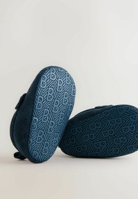 Tumesinised pehmed sussid tekstureeritud kummipõhjadega, millel on geomeetrilised mustrid ja kõrgendatud "B" logod. Turvalise kinnituse tagamiseks on paigaldatud takjakinnisrihm.