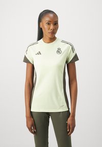Maglietta atletica verde chiaro con dettagli verde scuro, maniche corte, colletto a girocollo e logo sportivo Adidas con design di emblema regale.