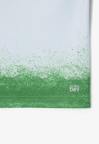Ljusblå träningsskjorta med ett gradientmönster av gröna stänk på botten. Har etiketten "ULTRA DRY" i vitt. Slät текстur.