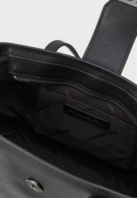 Μαύρη δερμάτινη τσάντα χειρός με εσωτερική θήκη με φερμουάρ και επένδυση με λογότυπο. Διαθέτει επίπεδο φερμουάρ και απαλή υφή. Μινιμαλιστικός σχεδιασμός.