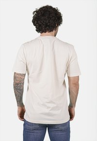 T-shirt in cotone color crema con maniche corte e vestibilità comoda, caratterizzato da un collo rotondo e orlo dritto. Nessuna grafica o motivo visibile.