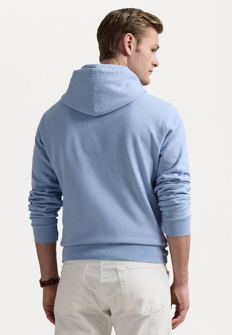 Sudadera azul claro con capucha ajustable, puños y dobladillo de canalé. La tela es suave, con un corte relajado y grosor medio.