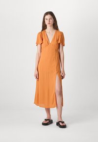 Orangen Midi-Kleid mit tiefem V-Ausschnitt, kurzen flatterhaften Ärmeln, seitlichem Schlitz und leichtem Stoff; kombiniert mit schwarzen flachen Sandalen.
