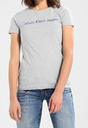 Szara bawełniana koszulka z krótkim rękawem, z niebieskim napisem "Calvin Klein Jeans" na przodzie. Standardowy krój i gładka tekstura.