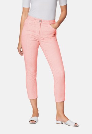 Korallenstreifen-Culotte mit hoher Taille, vorderen Taschen und Reißverschluss. Getragen mit weißen offenen Riemchensandalen und einem enganliegenden weißen Oberteil.