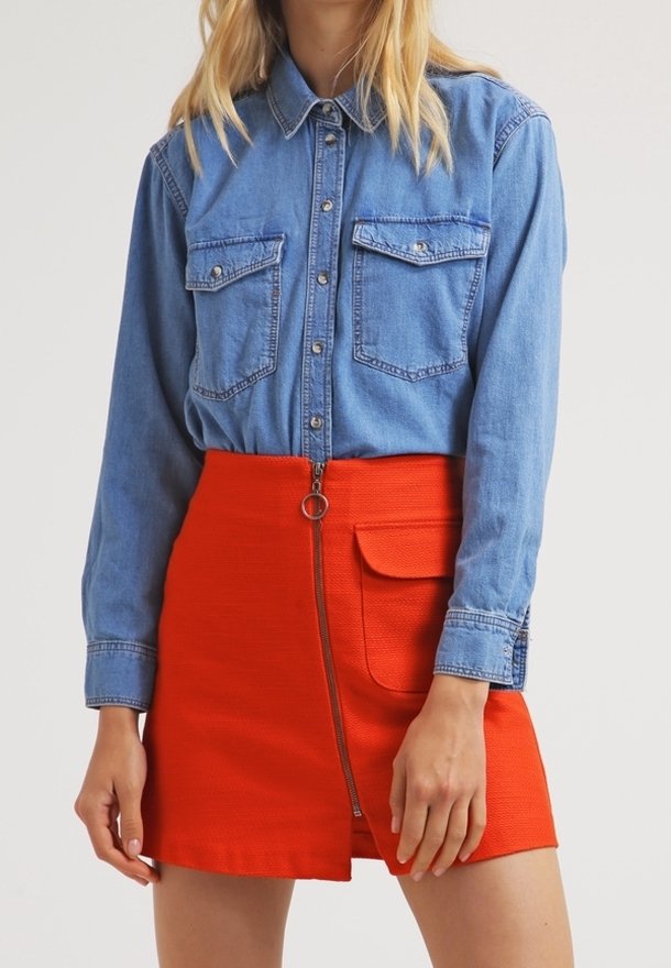 Denim skjorta med knappar och två bröstfickor, kombinerad med en klarorange minikjol med sidogylf och en lapplig ficka.