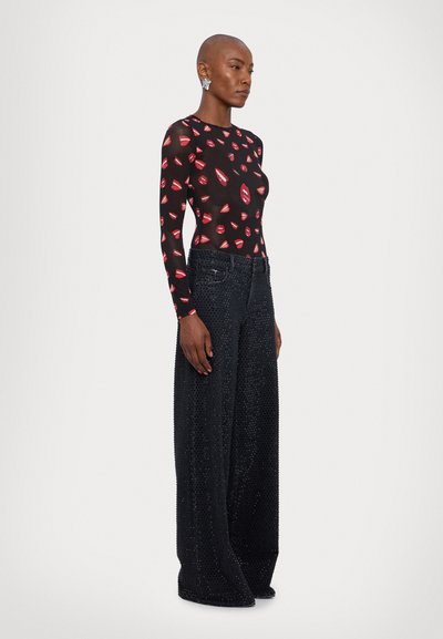 Body transparente negro con estampado de labios rojos, combinado con jeans negros de pierna ancha adornados con piedras de strass, que presentan un diseño clásico de cinco bolsillos.